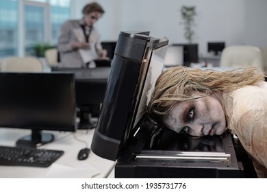 Young Spooky Businesswoman With Zombie Greasepaint On Face Keeping Head On Screen Of Xerox Machine