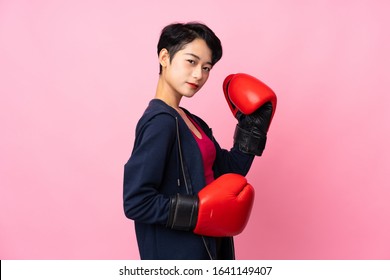Young sport Asian woman over isolated pink background with boxing gloves