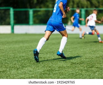 Young sport boys in blue sportswear running and kicking a  ball on pitch. Soccer youth team plays football in summer. Activities for kids, training	