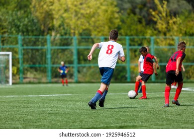 Young Sport Boys In Red Sportswear Running And Kicking A  Ball On Pitch. Soccer Youth Team Plays Football In Summer. Activities For Kids, Training	