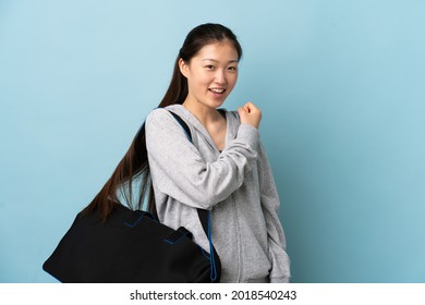 Young Sport Chinese  Woman With Sport Bag Over Isolated Blue Background Celebrating A Victory