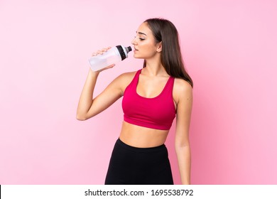 Young Sport Girl Over Isolated Pink Background With Sports Water Bottle