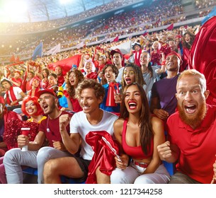 Young Sport Supporter Happy Fans Cheering At Stadium. Group Of Young Woman And Man Support The Football Team During The Match