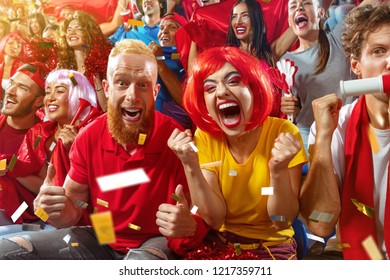 Young Sport Supporter Happy Fans Cheering At Stadium. Group Of Young Woman And Man Support The Football Team During The Match