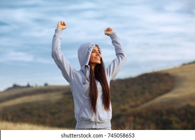 Young Sport Woman With Raised Arms Motivates Herself In Nature