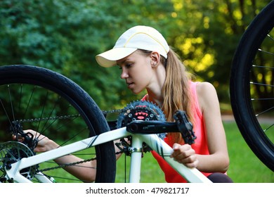 Young sport woman repairs her bicycle outdoor - Powered by Shutterstock