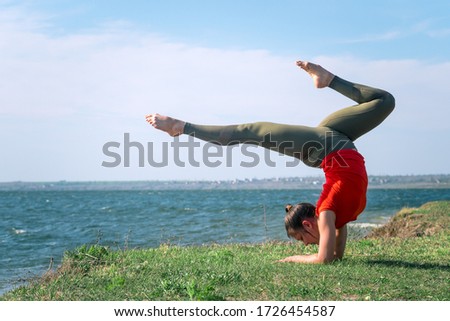 Young sport woman training a yoga hand standing near river