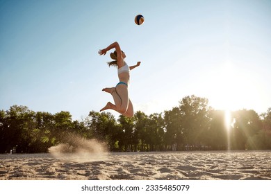 Young sportive, athletic woman in swimsuit playing beach volleyball outdoors on sand near river. Fresh air and training. Concept of sport, active and healthy lifestyle, hobby, summertime, ad - Powered by Shutterstock