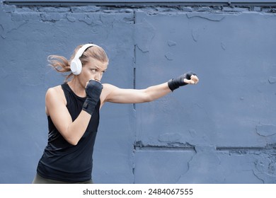 young sportive blond female boxer training , ready to punch, urban gray wall background - Powered by Shutterstock