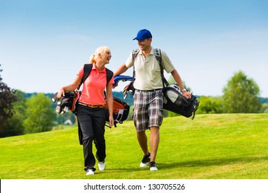 Young sportive couple playing golf on a golf course, they walking to the next hole - Powered by Shutterstock