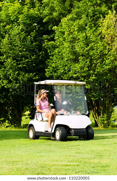 Young sportive couple playing golf on a golf\
course, they driving with golf\
cart