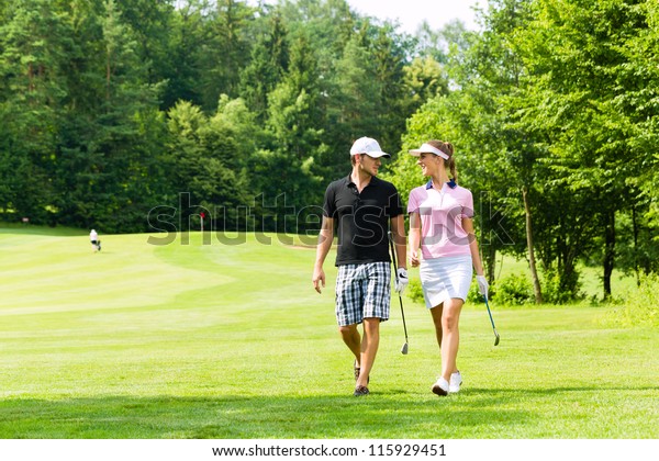 ゴルフ場でゴルフをする若いスポーティブカップルは 次のホールに向かって歩く の写真素材 今すぐ編集