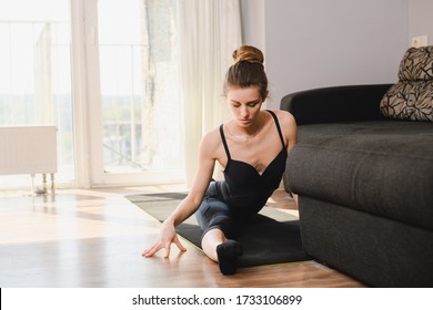 Young Sportive Female Sit On Mat In Split Twine, Professional Dancer, Trainer, Wearing Black Leotard, Home Activity During Isolation