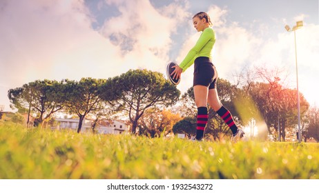 young sportive girl in uniform of rugby football player in a field. American football woman player in action holding a ball. Sport and lifestyle concept - Powered by Shutterstock