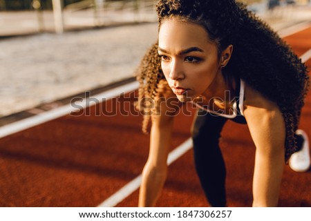 Young sportive woman runner at stadium starting line getting ready for race, sport concept