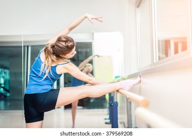 Young sportive woman stretching legs in a gym - Pretty girl doing a ballet exercise - Powered by Shutterstock