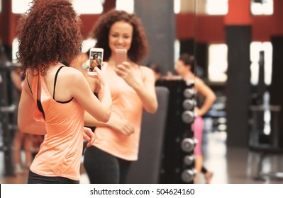 Young Sportive Woman Taking Selfie Near Mirror In Gym