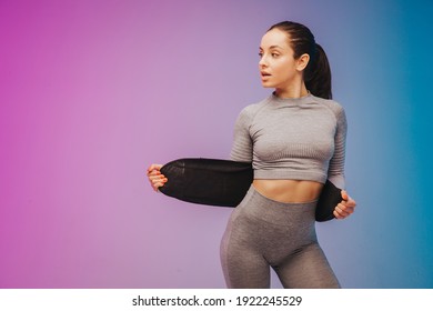 Young Sportive Woman Training Fitness Waist Trainer Belt Back Isolated On Gradient Studio Background In Neon Light. Modern Sport, Action, Motion, Youth Concept.