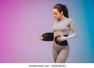 Young sportive woman training fitness waist trainer belt back isolated on gradient studio background in neon light. Modern sport, action, motion, youth concept