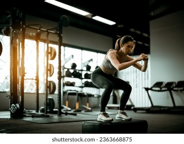 Young Sportive Woman Workout Exercising with Jumping Step Platform at Fitness Center or Gym. Fitness and Wellness Concept - Powered by Shutterstock