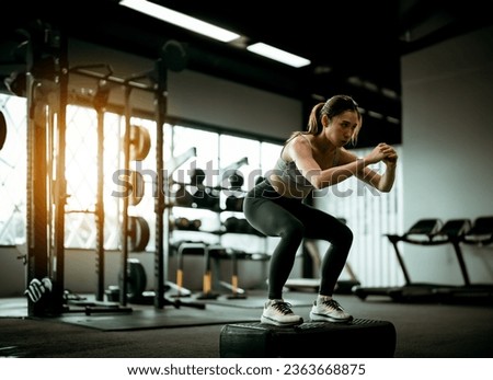 Young Sportive Woman Workout Exercising with Jumping Step Platform at Fitness Center or Gym. Fitness and Wellness Concept Foto stock © 