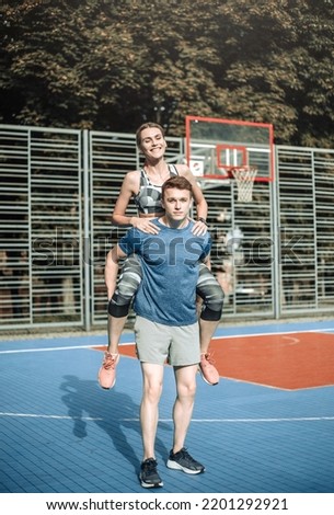 Young sports couple having fun hugging on the basketball court, leisure actitvities outdoors
