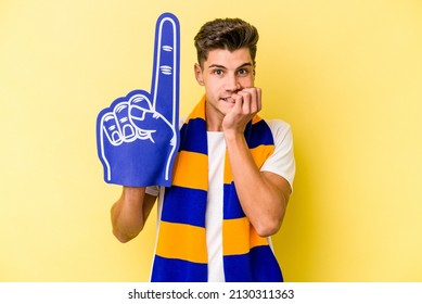 Young Sports Fan Man Isolated On Yellow Background Biting Fingernails, Nervous And Very Anxious.