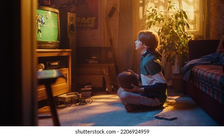 Young Sports Fan Watches American Football Match On TV At Home. Curious Boy Supporting His Favorite Team, Feeling Proud When Players Score A Goal. Nostalgic Retro Childhood Concept.