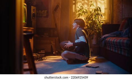 Young Sports Fan Watches American Football Match On TV At Home. Handsome Boy Supporting His Favorite Team. Nervously Playing With Football. Nostalgic Retro Childhood Concept.