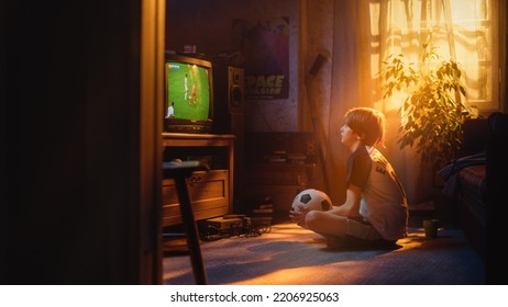 Young Sports Fan Watches A Soccer Match On TV At Home. Curious Boy Supporting His Favorite Football Team, Feeling Proud When Players Score A Goal. Nostalgic Retro Childhood Concept.