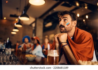 Young Sports Fan Watching A Match With Anticipation In  Bar.