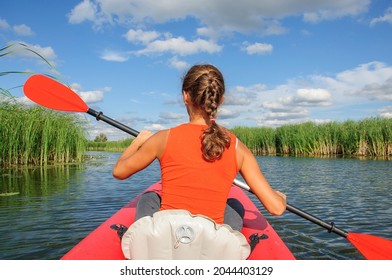 A Young Sports Girl Floats On The Zdwyzh River On A Red Kayak With A Black Dog Cocker Spaniel. Ukraine