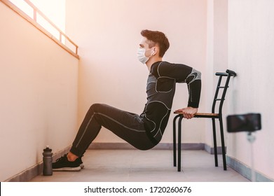 Young sports man in protective mask doing triceps dips on chair against phone camera. Athletic man fitness coach, blogger influencer record video tutorial. Home workout training. COVID-19 quarantine