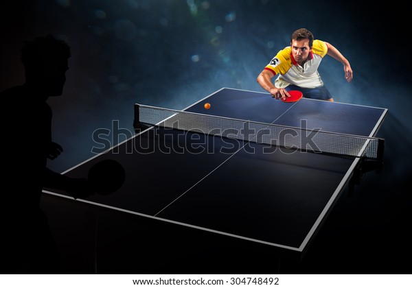 young sports man tennis player is playing on black\
background with lights