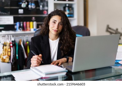 Young Sports Psychologist With Laptop Making Notes And Looking At Camera During Work In Modern Gym In Daytime