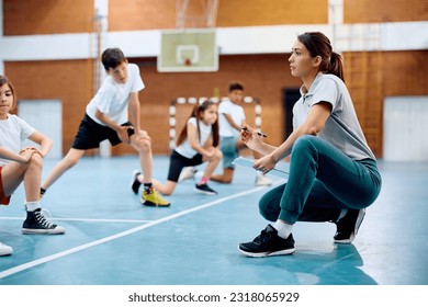 Young sports teacher talking to children during physical education class at school gym.  - Powered by Shutterstock