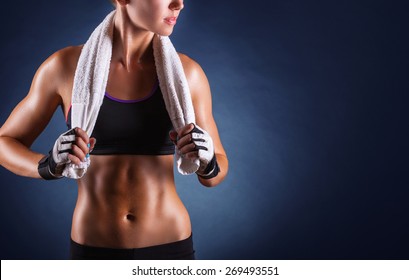 Young Sports Woman After Workout With Towel On His Shoulders On A Dark Background