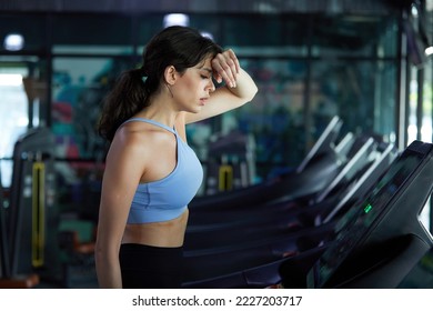 young sports woman working out, running and feeling tired on treadmill in gym