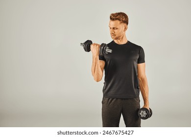 A young sportsman in active wear lifting dumbbells in a studio with a white background. - Powered by Shutterstock