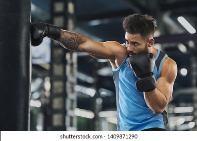 Young sportsman boxing workout at gym, guy punching boxing bag, free space