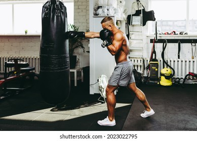 Joven deportista entrenando en gimnasia y en una bolsa de boxeo de punching. Un chico entrena en un gimnasio y pone su bolso de boxeo. Concepto de gimnasio, fitness, concepto de boxeo.