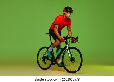 Young Sportsman, Cyclist On Bicycle In Sports Uniform And Protective Helmet Training Isolated On Green Background. Concept Of Active Life, Rest, Travel, Energy, Sport. Copy Space For Ad