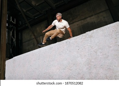 Young sportsman doing parkour in city. Athlete is practicing freerunning outdoors on the streets. Art of motion, modern urban sport. Extreme sport concept. Copy space - Powered by Shutterstock