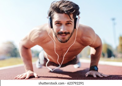 Young Sportsman Doing Push Ups And Listening To Music With Headphones. Sport, Fitness, Street Workout Concept