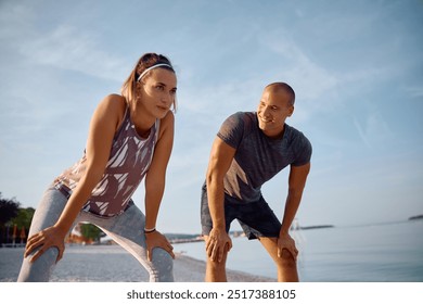 Young sportsman and his female friend resting after jogging on the beach.  - Powered by Shutterstock