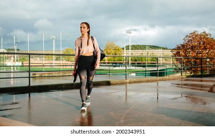 Young sportswoman with gym bag and sports shoes walking to go to training - Powered by Shutterstock