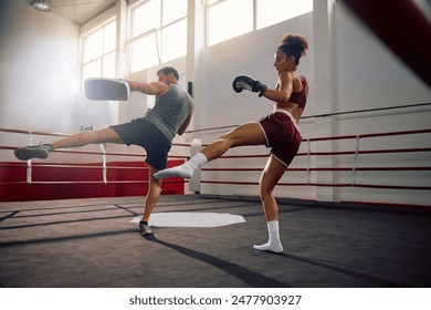 Young sportswoman and her boxing coach practicing in health club.  - Powered by Shutterstock