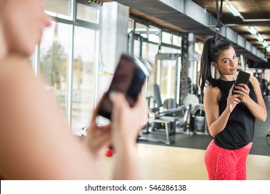 Young Sportswoman With Smartphone Taking Mirror Selfie In Gym.