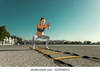 Young Sportswoman Training Jumping On An Agility Ladder Coordinating Outdoors