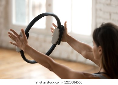 Young sporty attractive woman doing pilates toning exercise for arms and shoulders with ring, fitness with pilates magic circle in hands, working out, indoor close up. Strength, well being concept - Powered by Shutterstock